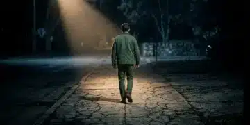 A person walking on a cracked sidewalk, illuminated by a single dramatic light beam, symbolizing early cultural shifts and subtle societal indicators.